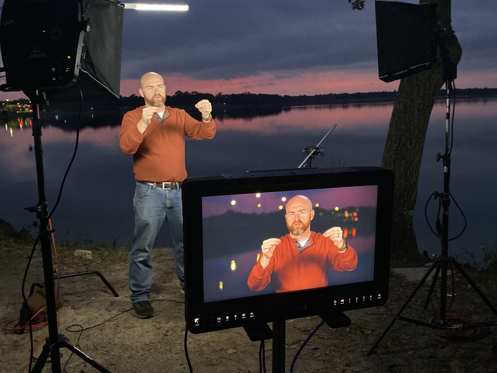 Scott Withers filming a weather segment at dusk by the water